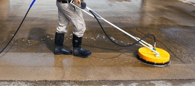 A homeowner pressure washing the driveway after determinig what is a good PSI for the pressure washer