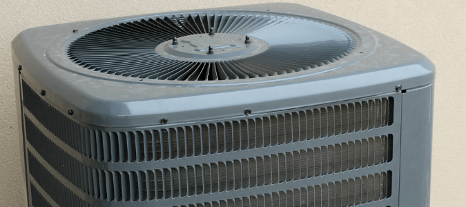 A gray outdoor air conditioning unit with dirty condenser coils