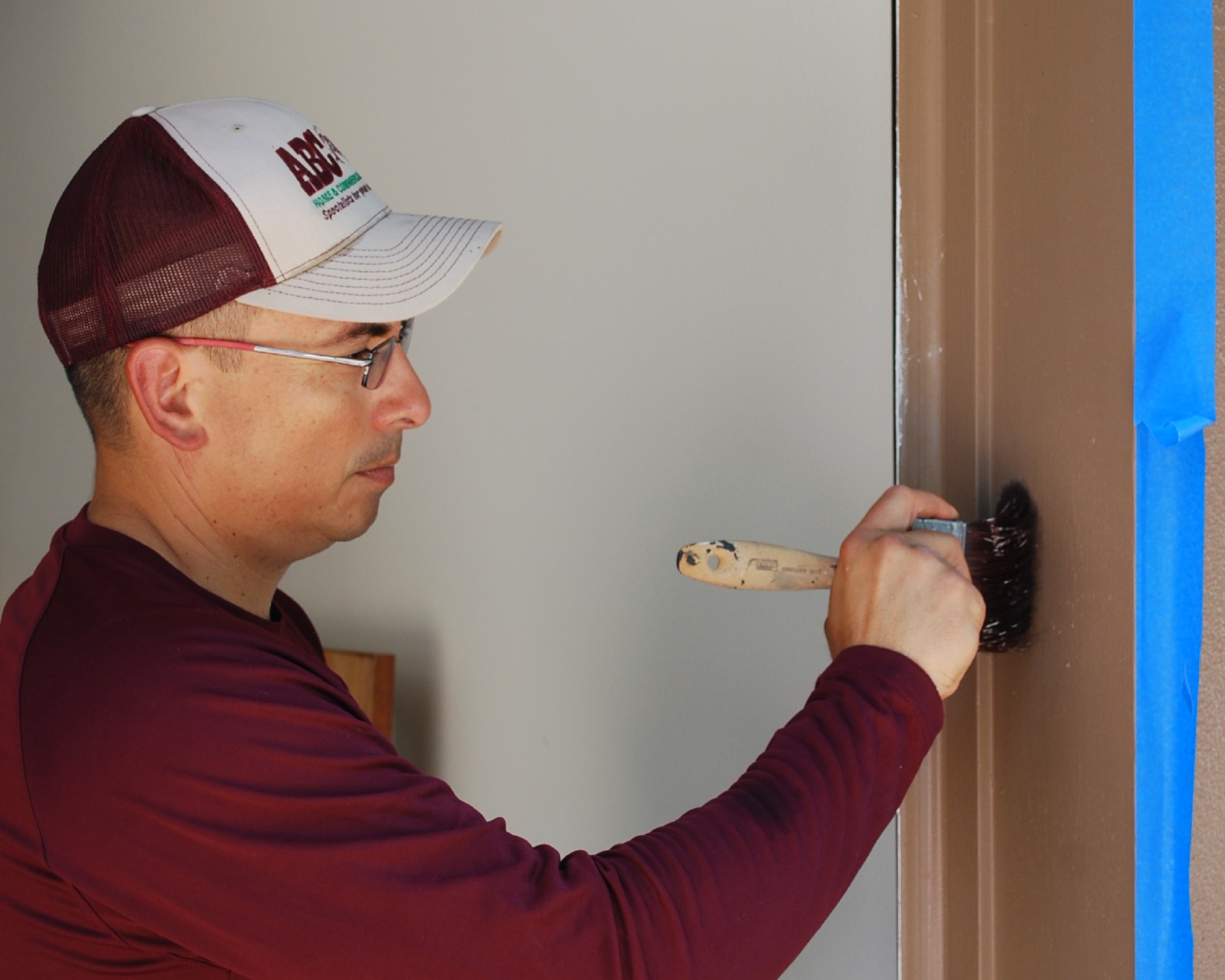 an ABC employee painting some trim in a house
