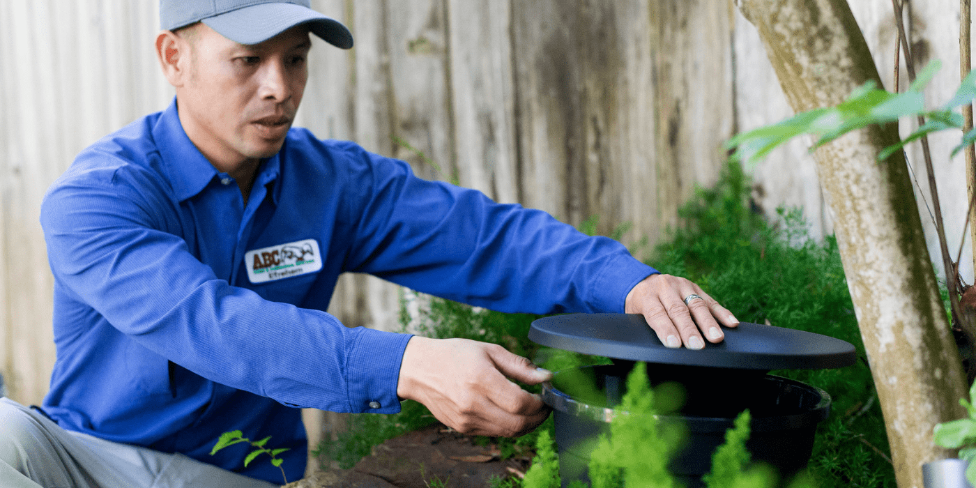 un especialista en control de plagas instalando estaciones de nebulización para mosquitos en un patio