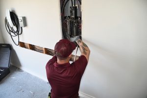 An electrician working on an electrical panel in a garage