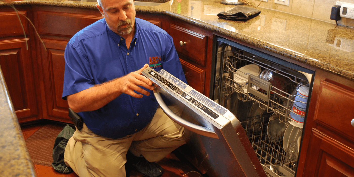 an appliance repair specialist doing tune-up servcie on a dishwasher