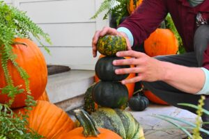 hands placing pumpkins on a porch