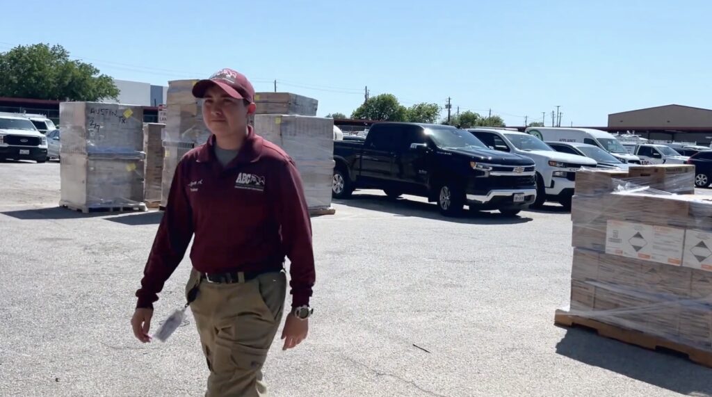 A pest technician in an ABC uniform walking through a parking lot
