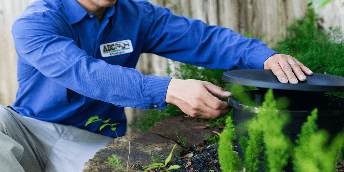 a pest control specialist setting up mosquito misting stations in a yard