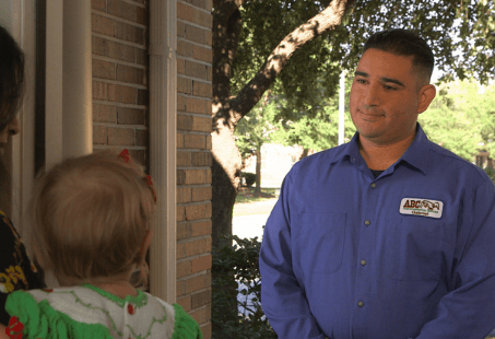 An ABC employee speaking with two customers at their front door.