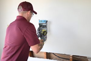 An electrician installing pieces of an EV charger on a wall.