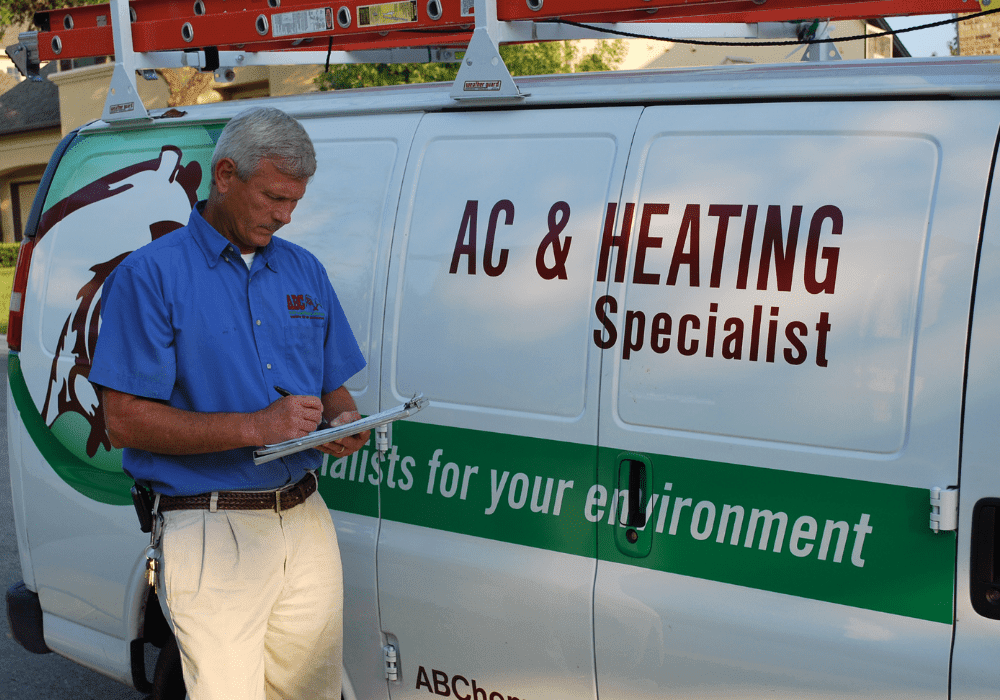 a heating and cooling specialist writing a report beside a work van