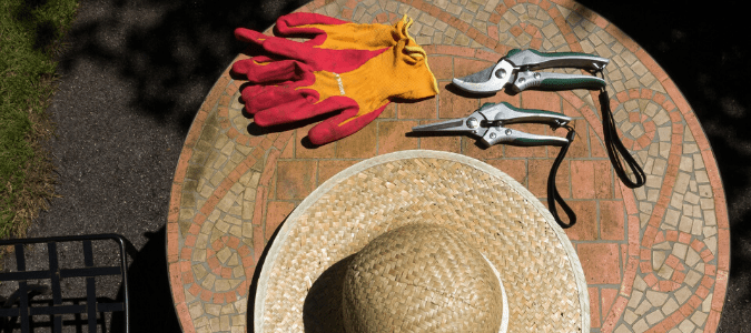 Gardening gloves, shears and a hat on an outdoor table