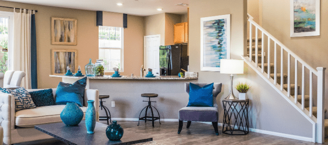 A grey and blue living room that leads to a kitchen