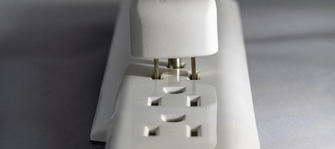 a white power strip that someone is plugging a device into