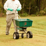 a lawn care specialist fertilizing a homeowner’s lawn