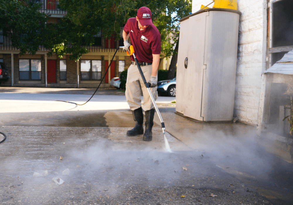 a specialist power washing a homeowner’s driveway