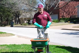An ABC employee, pushing lawn equipment, working on a customer's yard
