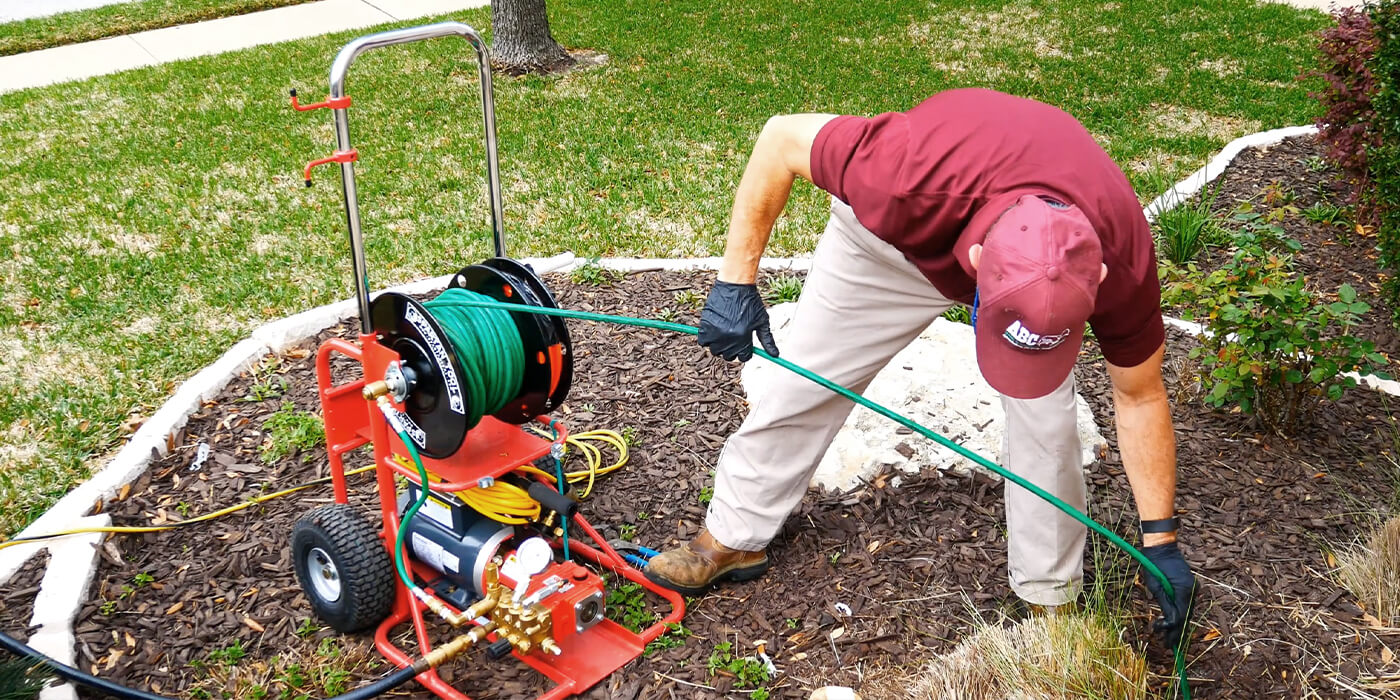 an ABC plumbing specialist feeding a hose down a drain