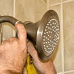an ABC plumbing specialist fixing a shower head