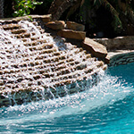 an outdoor pool remodeled with water cascading down stone steps