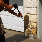 a specialist power washing a home’s stone exterior