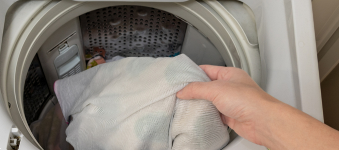 putting clothes into a washing machine