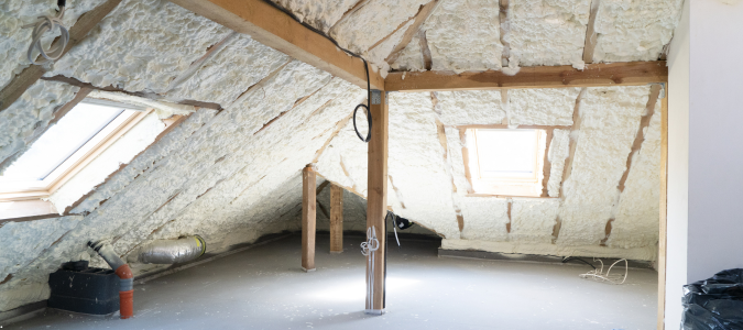 an unfinished home attic with insulation and beams showing