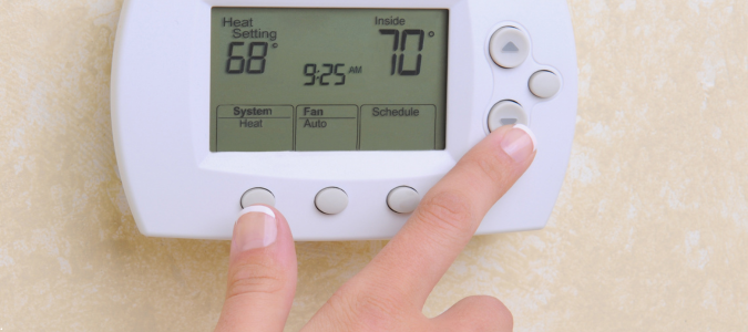 fingers adjusting a digital thermostat