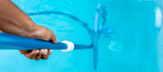 a specialist cleaning a pool with a vacuum