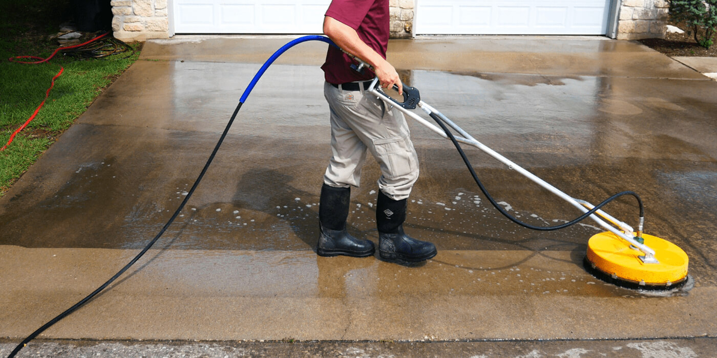 a specialist power washing a homeowner’s driveway
