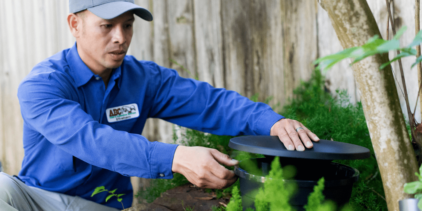 a pest control specialist setting up mosquito misting stations in a yard