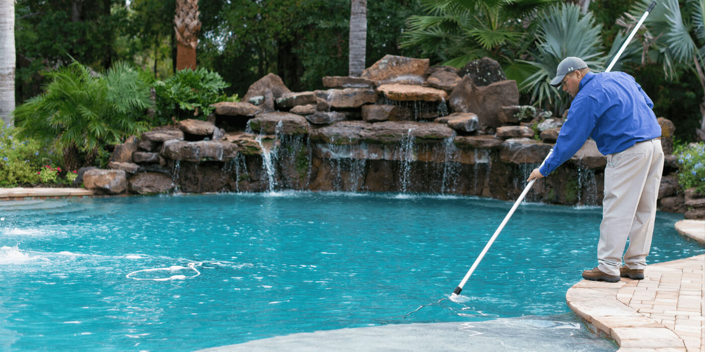 a certified pool professional cleaning a homeowner’s pool