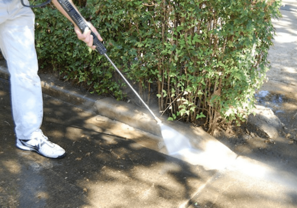 a commercial specialist power washing a sidewalk outside of a business