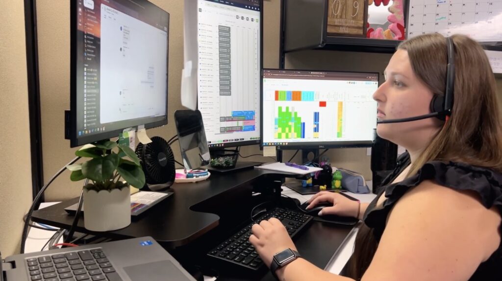 A dispatcher in the office, talking on a headset and looking at computer screens